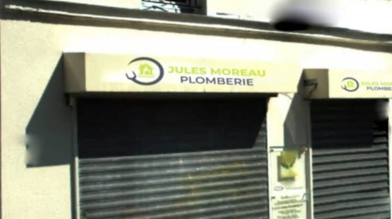 Devanture du magasin Jules Moreau Plomberie avec un panneau d'enseigne jaune et vert indiquant le nom de l'entreprise au-dessus des rideaux métalliques fermés.